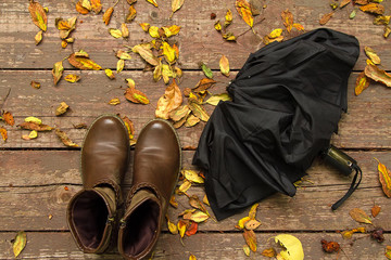 autumn boots and umbrella on wooden covered leaves floor