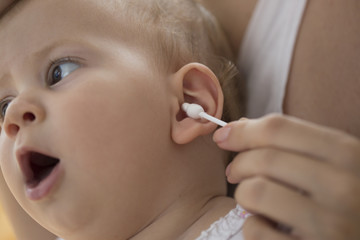 mother cleaning babies ear with cotton swabs