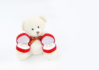 Golden wedding rings in red box at toy bears paws.