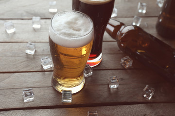 Bottles and glasses with cold beer on wooden background