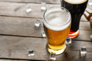 Glasses with cold beer on wooden background