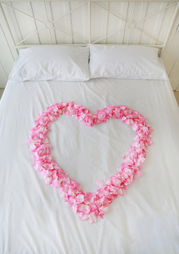 Heart of red petals on a bed. Honeymoon.