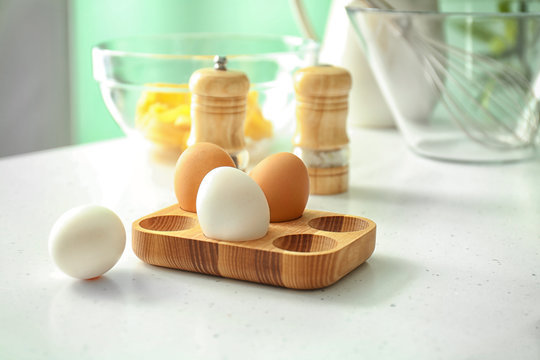 Wooden holder with chicken eggs on kitchen table