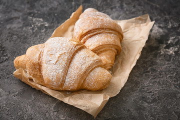 Parchment with tasty croissants on grey textured background