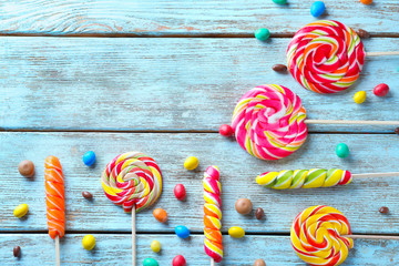 Composition with colorful lollipops on light wooden background
