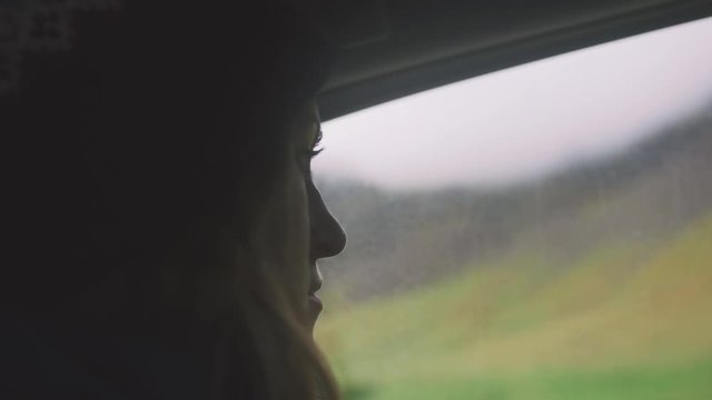 Young woman sitting inside the car and looking outside the window, silhouette, cinematic shot