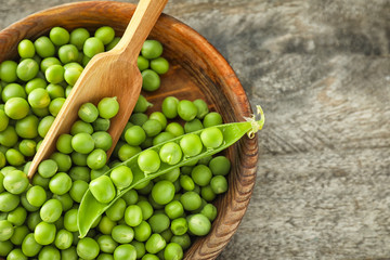 Bowl with delicious fresh green peas on wooden table