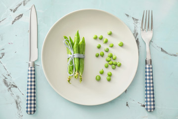Plate with delicious fresh green peas on color background