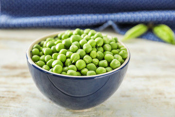 Bowl with delicious fresh green peas on white wooden table