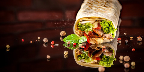 Two burrito, black and white lavash with chicken, mushrooms, salad, cherry tomatoes, lime, and salsa. Copy space, selective focus