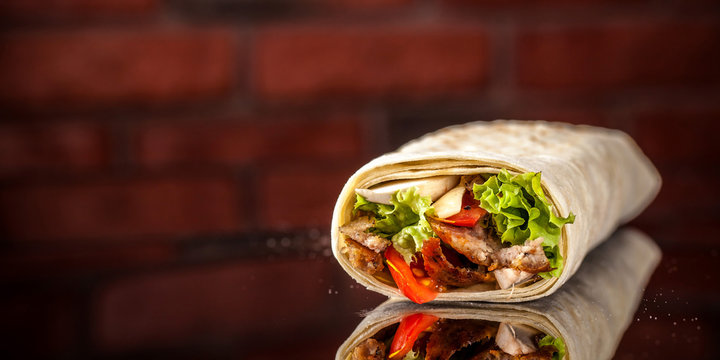 Two burrito, black and white lavash with chicken, mushrooms, salad, cherry tomatoes, lime, and salsa. Copy space, selective focus