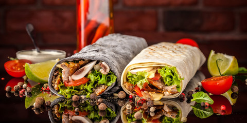 Two burrito, black and white lavash with chicken, mushrooms, salad, cherry tomatoes, lime, and...