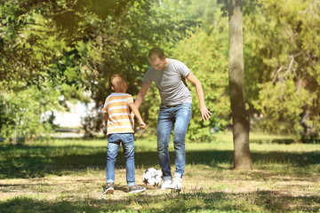 Fototapeta premium Happy father and son playing football in park