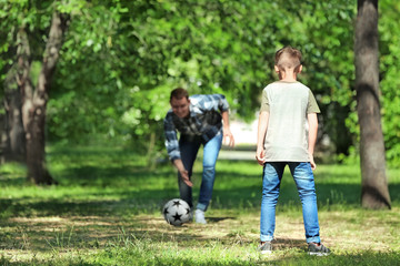 Fototapeta premium Happy father and son playing football in park