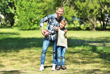 Happy father and son with rugby ball in park
