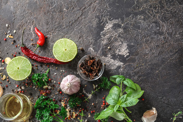 Various spices and herbs with lime and oil on grey background