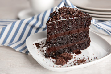 Plate with piece of delicious chocolate cake on wooden table