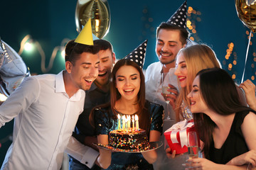 Young woman with friends and birthday cake in club