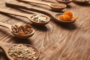 Spoons with various healthy products on wooden table