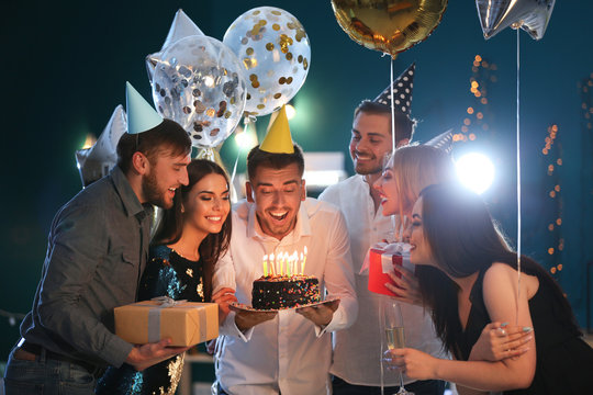 Young Man With Friends And Birthday Cake In Club