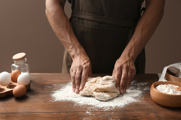 Man kneading dough on wooden table