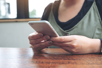Closeup image of a woman holding , using and looking at smart phone in cafe