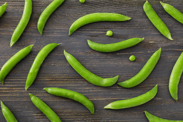 Pods with fresh green peas on wooden background, flat lay