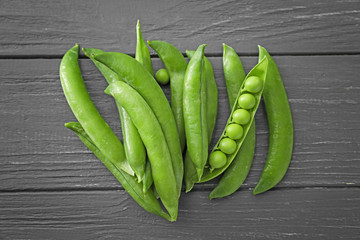 Pods with fresh green peas on wooden background