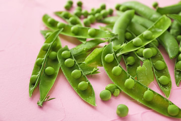 Pods with fresh green peas on color background