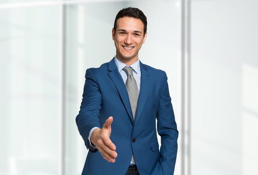 Smiling young businessman giving an handshake