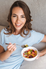 Cheerful young woman eating healthy breakfast