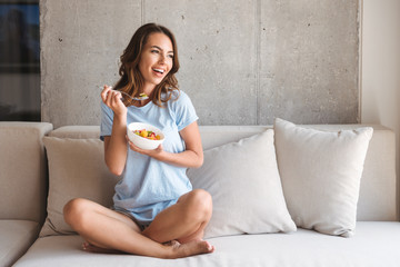 Happy young woman eating healthy breakfast