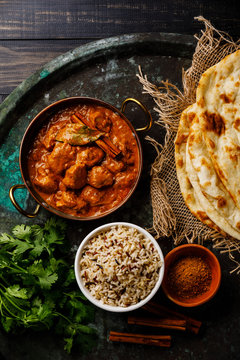 Chicken tikka masala spicy curry meat food with rice and naan bread on dark background