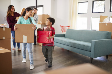 Excited Family Carrying Boxes Into New Home On Moving Day