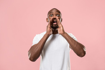 Isolated on pink young casual man shouting at studio