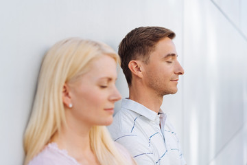 Young couple standing meditating with closed eyes