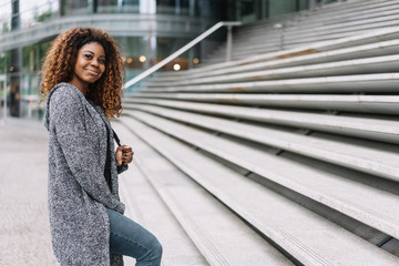 Portrait of smiling black woman standing by steps