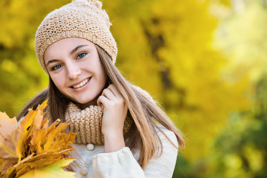 Young pretty girl portrait with yellow mapple leaf closed face by autumn bouquet