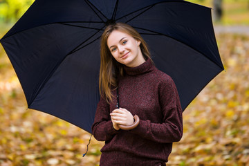 Girl hold umbrella on yellow autumn leaves background