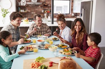 Multi Generation Family Enjoying Meal Around Table At Home Together