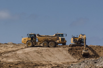Obraz premium CONSTRUCTION MACHINERY - Tipper trucks and excavator on construction side 