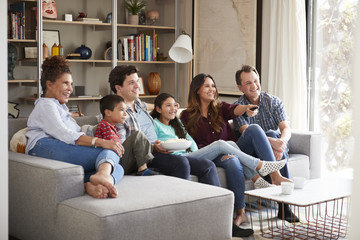 Multi Generation Family Relaxing On Sofa At Home Watching Television