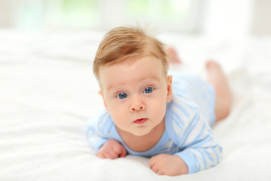 Beautiful baby with blue eyes lying on the bed.