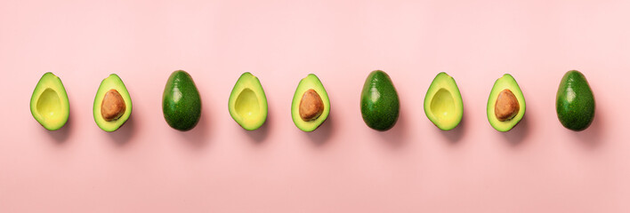 Organic avocado with seed, avocado halves, whole fruits on pink background. Top view. Banner, seamless pattern. Pop art design, creative summer food concept. Green avocadoes, minimal flat lay style.