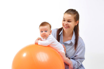 Mom and baby doing gymnastics on an orange fitball.