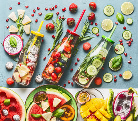 Summer refreshing and extra hydrating infused water in bottles with ingredients, top view. Various...
