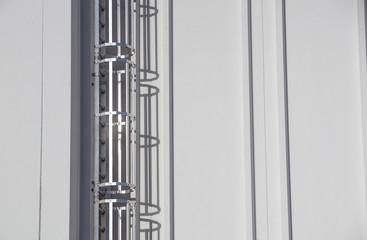 Steel ladder with protection, attached to an industrial, production hall or building.