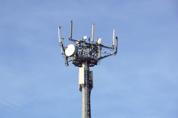 Antenna tower of telecommunication and signal repeater of mobile communication with blue sky, over building