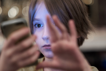 The face of the child, illuminated by the screen of the phone in his hands