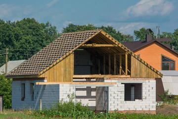 Fototapeta na wymiar House building construction from aerated concrete blocks. Wooden roof under construction